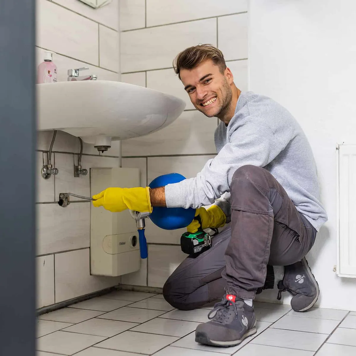 Techniker reinigt einen Abfluss unter dem Waschbecken