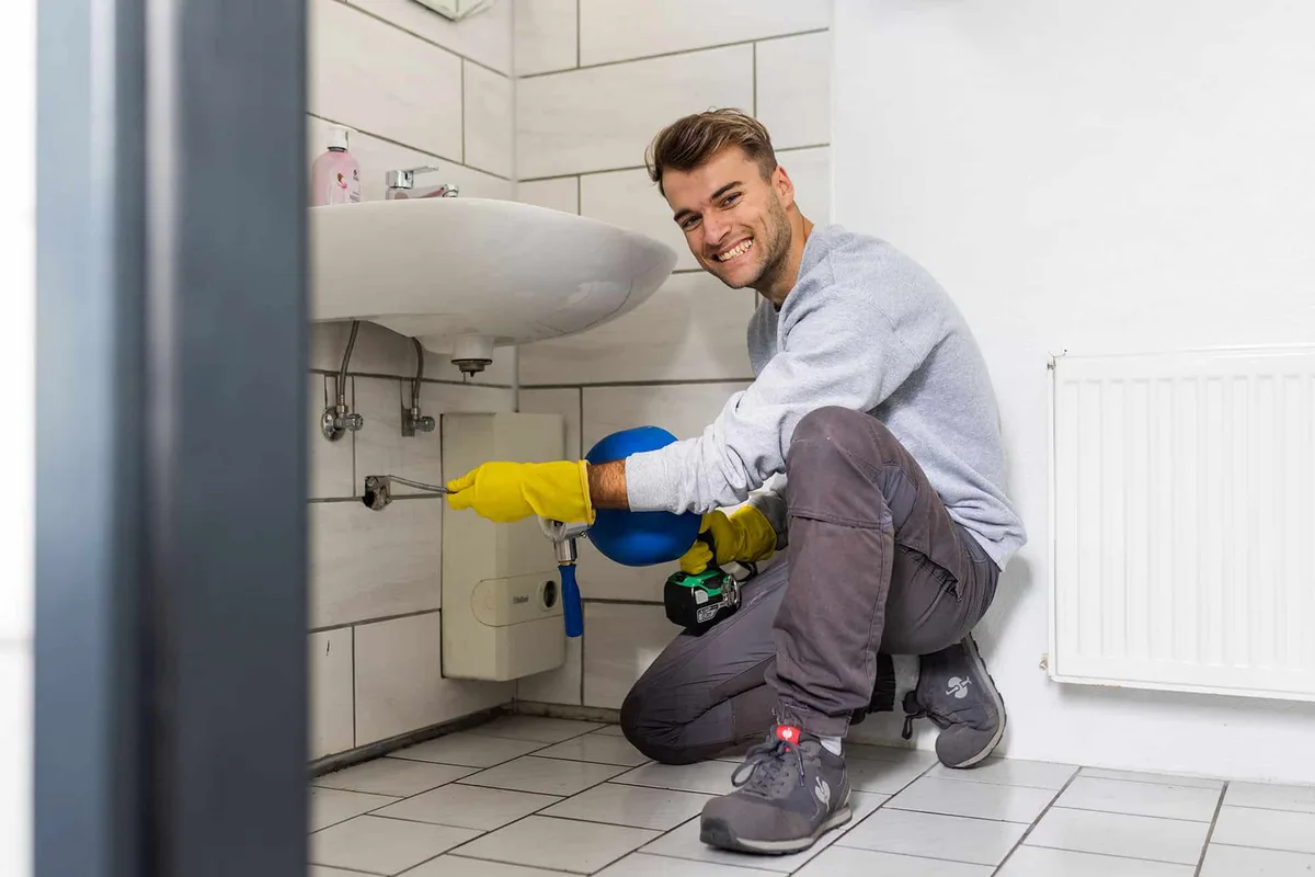 Techniker reinigt mit der Handspirale den Abfluss unter dem Waschbecken